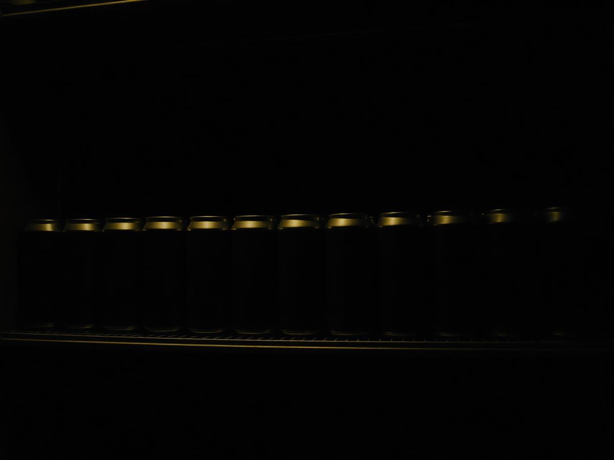 Row of unbranded beverage cans on a dimly lit retail shelf